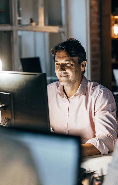 Happy businessman sitting at his computer